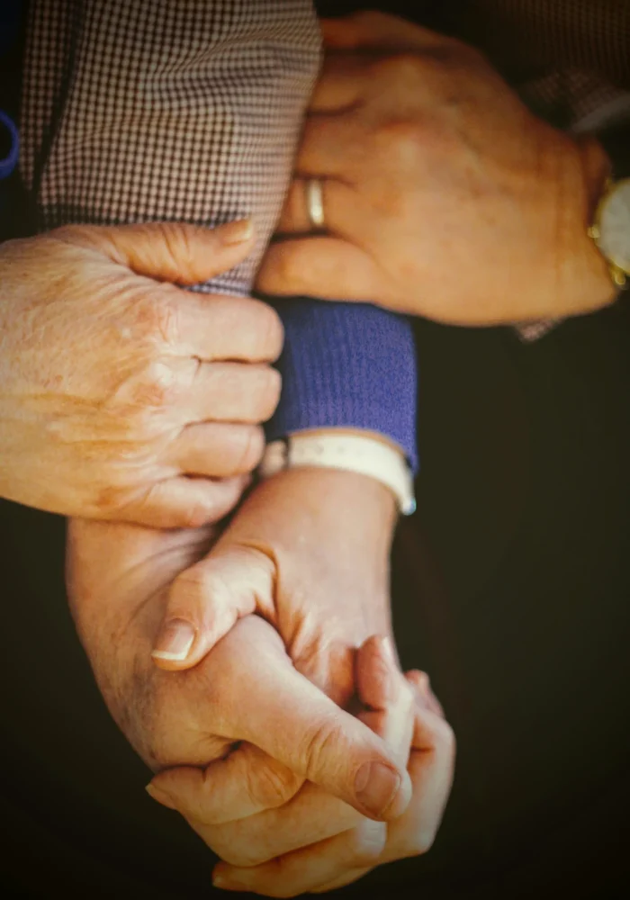 Caregiver holding an elderly person's hand while providing compassionate support and assistance
